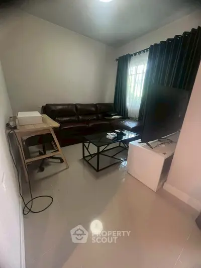 Cozy living room with leather sofa and modern TV setup, perfect for relaxation.