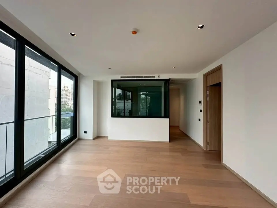 Spacious modern living room with large windows and wooden flooring in a luxury apartment.