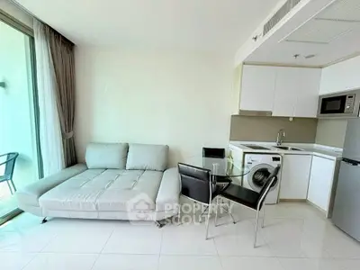 Modern living room with sleek kitchen, featuring a cozy sofa and compact dining area, perfect for urban living.