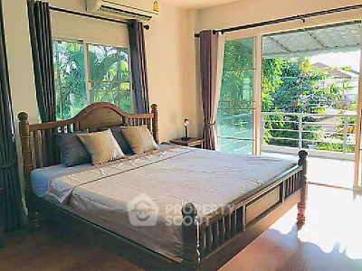 Spacious bedroom with large windows and balcony access, offering abundant natural light and serene views.
