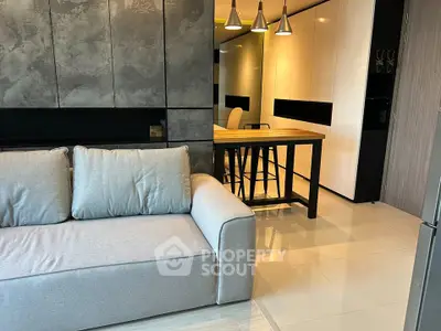 Modern living room with stylish decor and open kitchen layout, featuring sleek furniture and contemporary lighting.