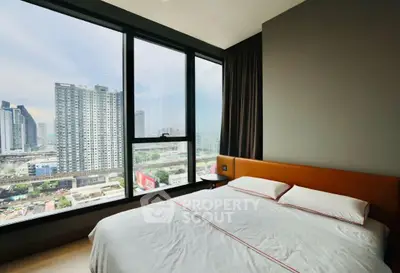 Modern bedroom with large windows offering stunning city views in a high-rise apartment.