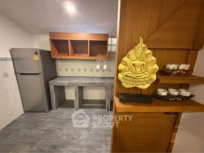 Modern kitchen with sleek design and Buddha decor, featuring a stainless steel fridge and ample storage.