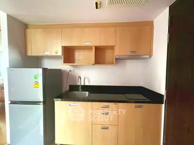 Compact kitchen with modern wooden cabinets and sleek black countertop