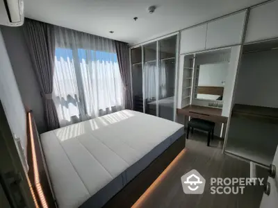 Modern bedroom with large window and built-in wardrobe in stylish apartment.