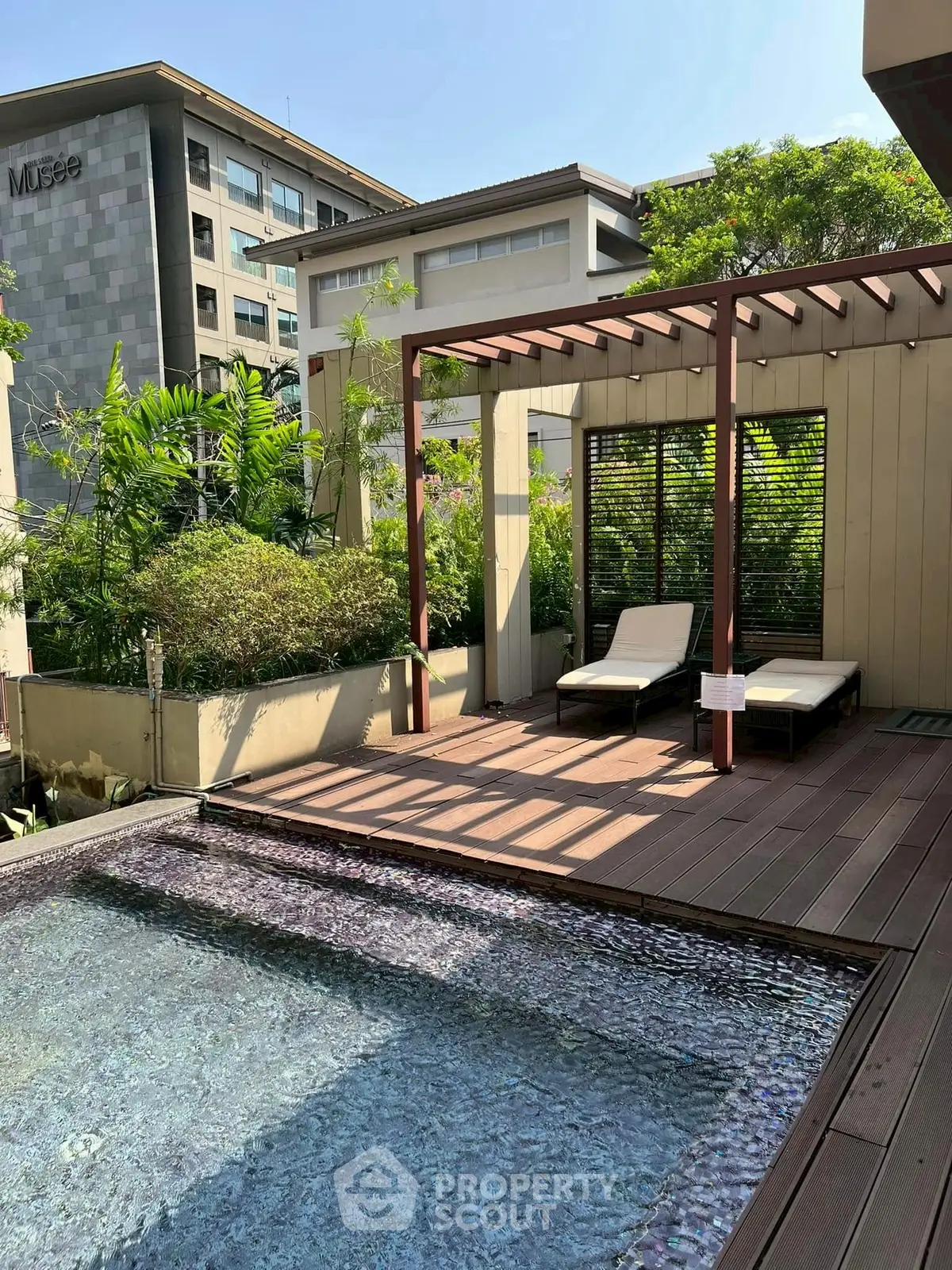 Luxurious rooftop pool with sun loungers and pergola, offering a serene urban escape.