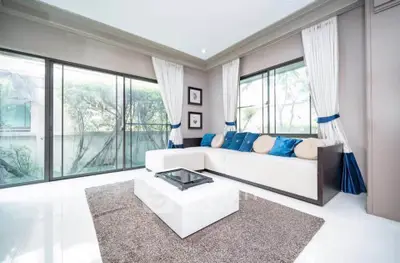 Spacious living room with modern decor and large windows offering garden views.