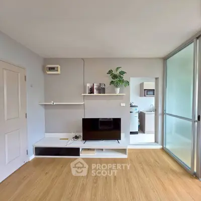 Modern living room with sleek TV setup and open kitchen view, featuring stylish wooden flooring and contemporary decor.