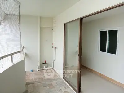 Spacious balcony with sliding glass doors and tiled flooring in modern apartment.