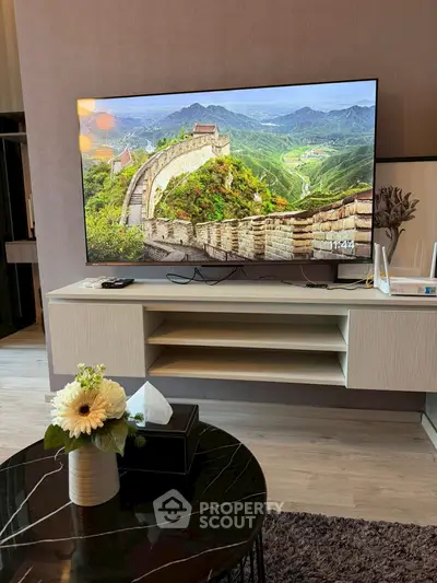 Modern living room with large TV and stylish decor, perfect for entertainment and relaxation.