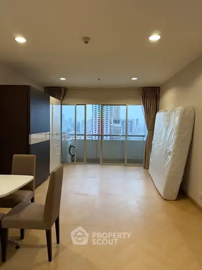 Spacious living room with city view and balcony access, featuring modern furniture and natural light.