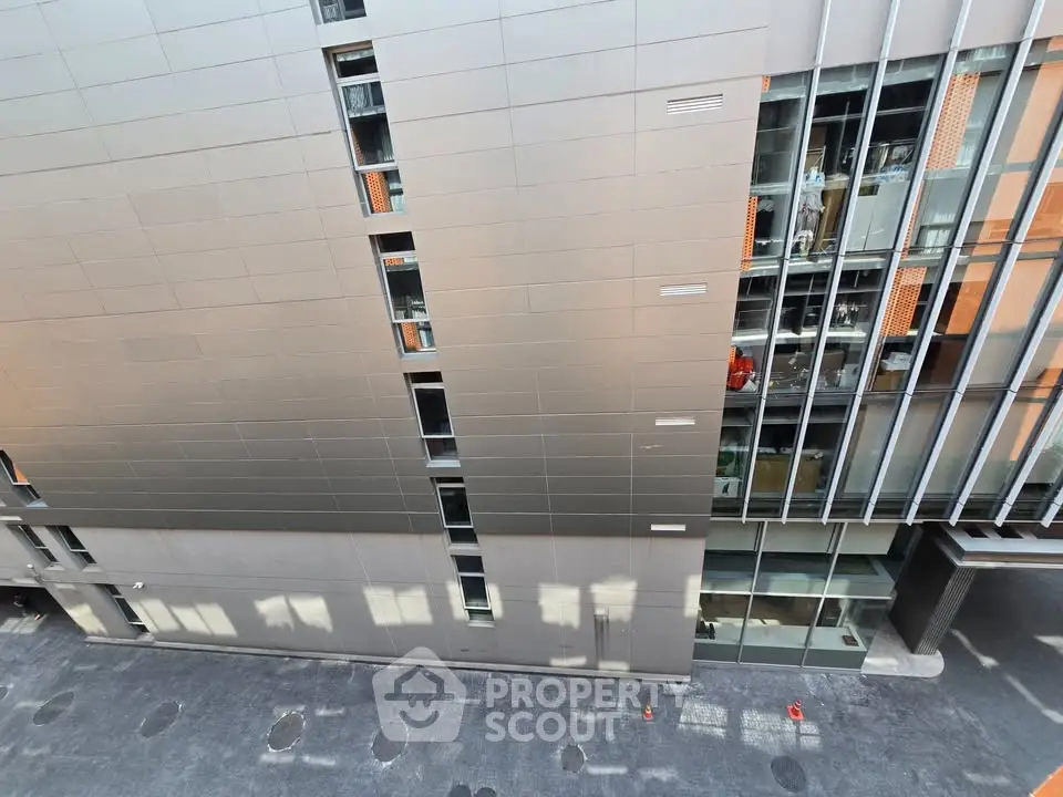 Modern urban building exterior with sleek metal facade and large windows.