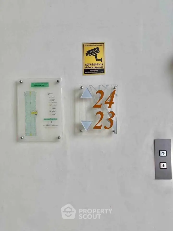 Modern elevator signage with floor numbers and CCTV notice in a residential building.