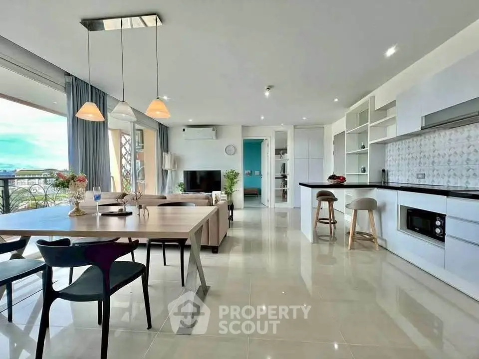 Spacious open-plan living room and kitchen with modern decor and ample natural light.