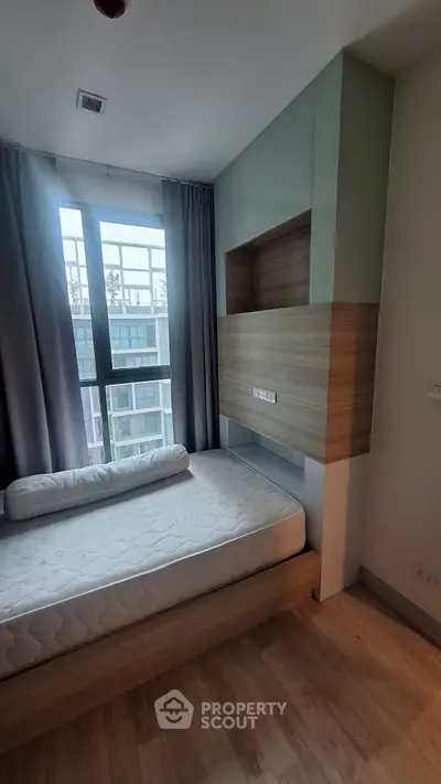 Modern bedroom with large window and built-in storage in urban apartment