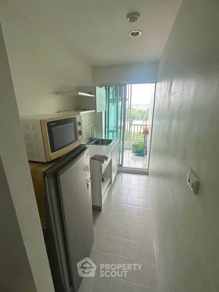Compact kitchen with modern appliances and balcony view in cozy apartment