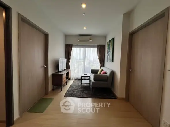 Modern living room with stylish decor and natural light, featuring a cozy sofa and flat-screen TV.