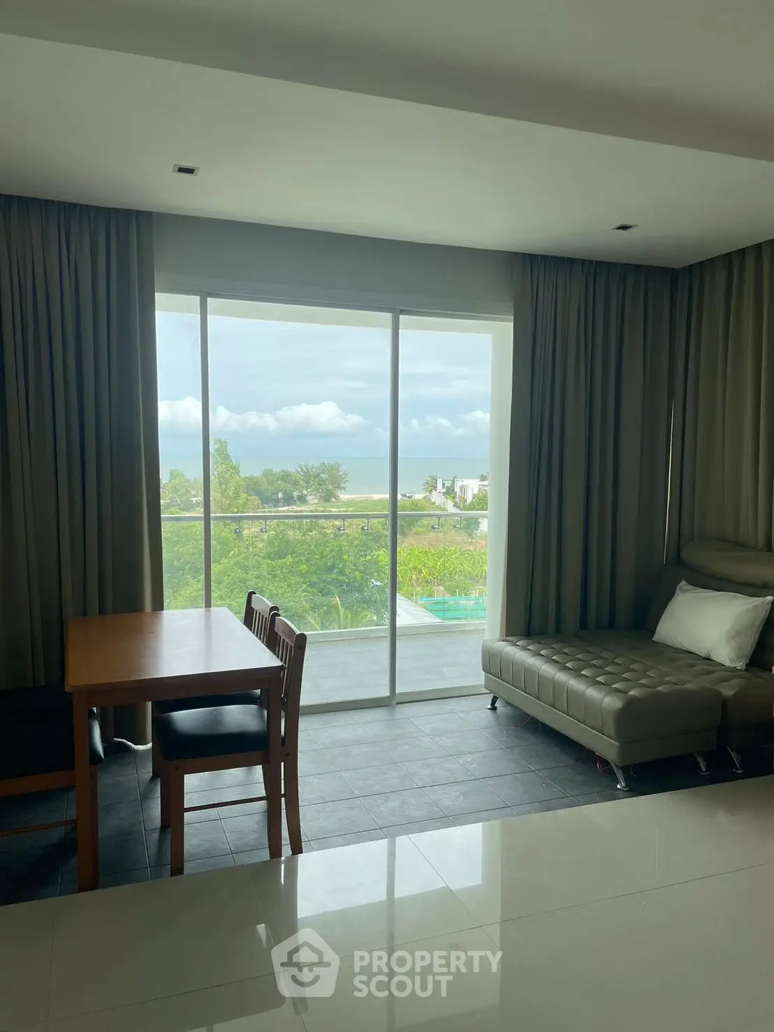 Modern living room with ocean view, featuring sleek furniture and large windows for natural light.
