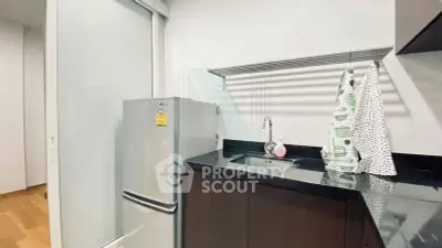 Modern kitchen with sleek black countertops and stainless steel fridge