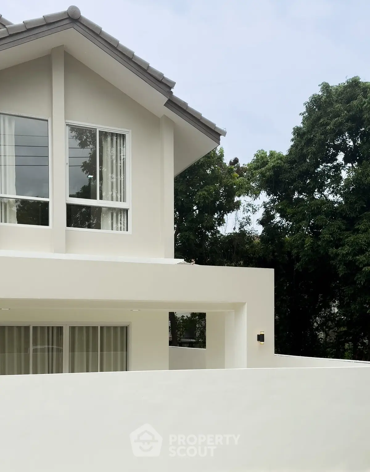 Modern two-story house exterior with large windows and lush greenery