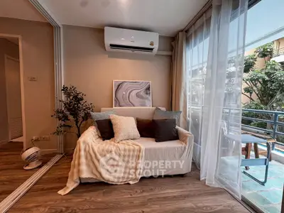 Cozy living room with modern decor and balcony view, featuring a comfortable sofa and air conditioning.