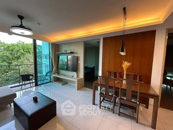 Modern living room with dining area and balcony view, featuring stylish lighting and contemporary decor.