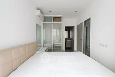 Modern bedroom with minimalist design and ensuite bathroom in a stylish apartment.