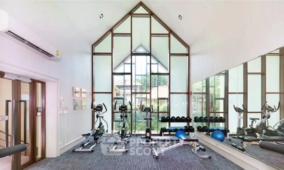 Modern gym with large windows and exercise equipment in a residential building.