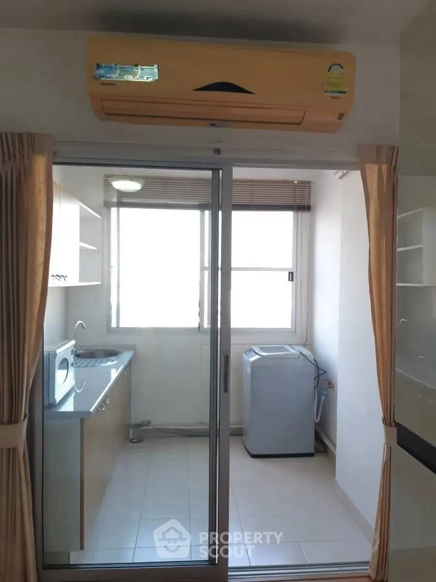 Modern kitchen with sliding glass door and washing machine, featuring ample natural light and efficient layout.
