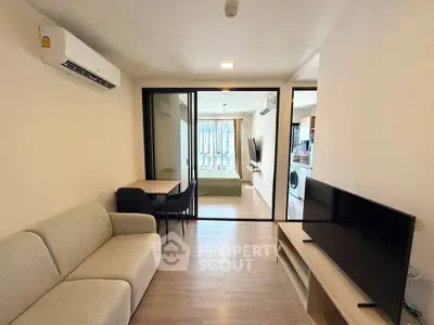 Modern living room with open layout, featuring a cozy sofa, dining area, and view into a bedroom.
