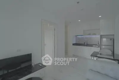 Modern open-plan living room with sleek kitchen and marble flooring in a stylish apartment.