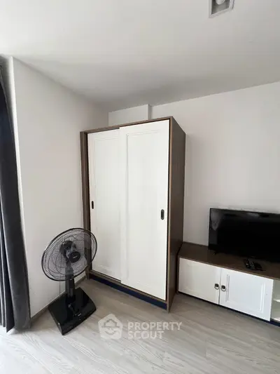 Modern bedroom with sleek wardrobe and TV stand, featuring stylish fan and minimalist decor.