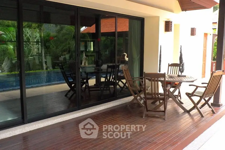 Luxurious patio with wooden deck and pool view, perfect for outdoor relaxation and entertainment.