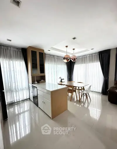 Modern kitchen with open layout and elegant dining area featuring natural light.