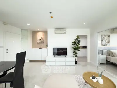 Modern open-plan living room with sleek furniture and neutral tones, featuring a cozy seating area and a stylish TV setup.