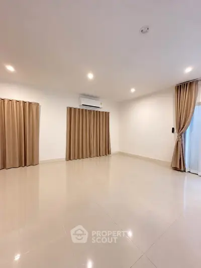 Spacious empty living room with elegant curtains and polished tile flooring.