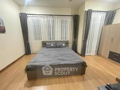 Spacious bedroom with modern decor and large windows for natural light.