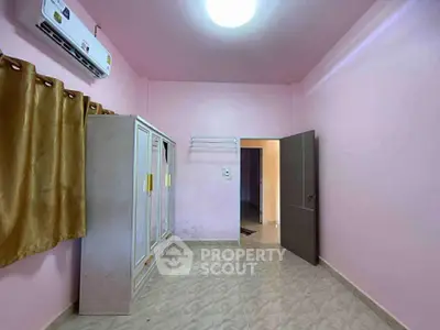Spacious bedroom with pink walls, wardrobe, and air conditioning unit.
