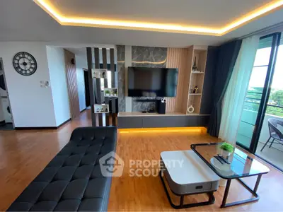 Modern living room with stylish decor, large TV, and balcony view in a luxurious apartment.