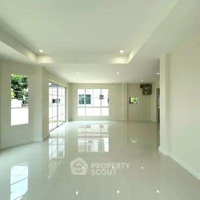 Spacious modern living room with large windows and glossy tiled floors in a bright, open layout.