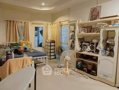 Spacious living room with modern decor and ample natural light, featuring cozy seating and stylish shelving.
