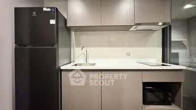 Modern kitchen with sleek cabinetry, built-in oven, and black refrigerator in a stylish apartment.