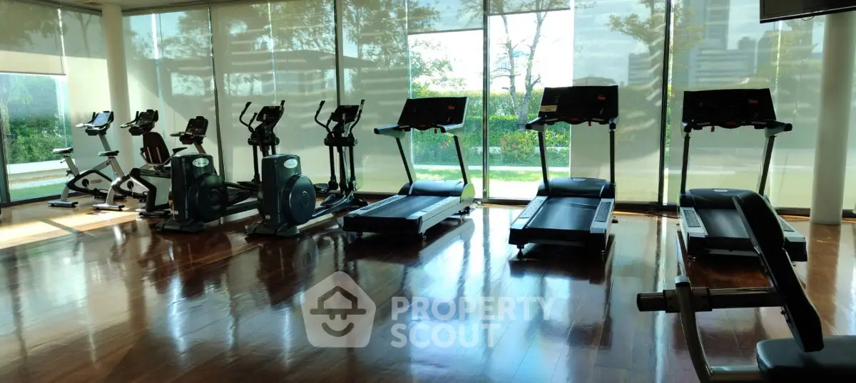 Spacious gym with modern equipment and large windows offering a scenic view, perfect for fitness enthusiasts.