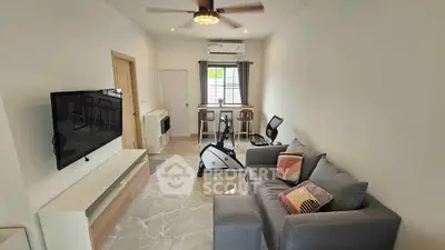 Modern living room with sleek furniture and exercise bike, featuring a wall-mounted TV and stylish decor.
