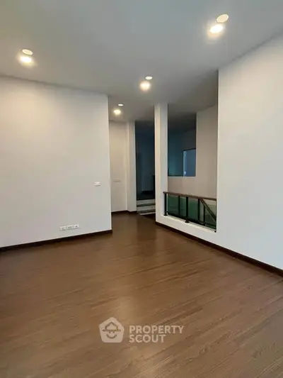 Spacious modern interior with wooden flooring and recessed lighting, ideal for versatile living space.