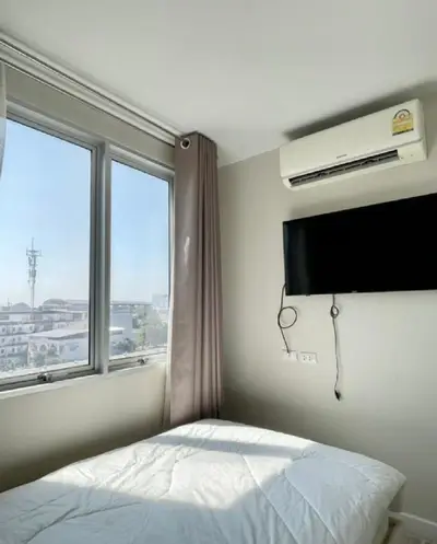 Bright bedroom with large window and wall-mounted TV, offering a cozy and modern living space.