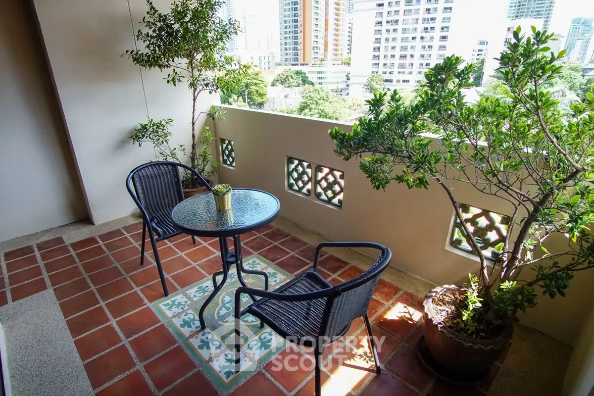 Charming balcony with city view, featuring cozy seating and lush greenery, perfect for relaxation.