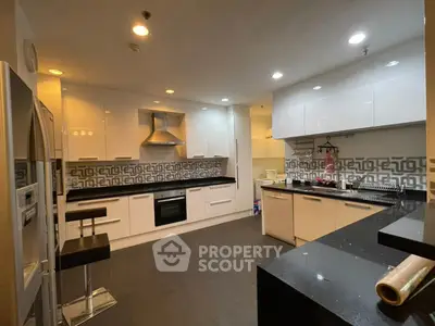 Modern kitchen with sleek white cabinets and black countertops, featuring a built-in oven and stylish backsplash.