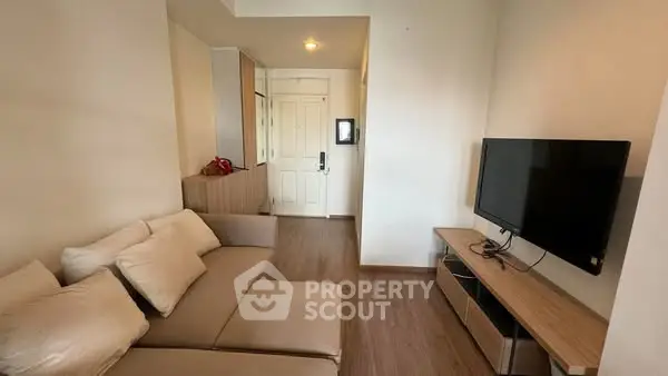 Modern living room with cozy beige sofa and flat-screen TV, perfect for relaxation.