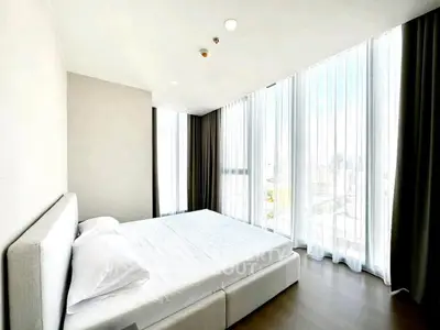 Spacious bedroom with floor-to-ceiling windows and city view